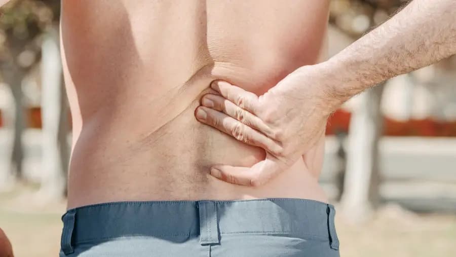 Desk-job lower back pain Bangalore — IT professional holding lumbar spine in pain, treated with McKenzie extensions, hip-hinge retraining and workplace ergonomics audit at Pro Physiotherapy JP Nagar